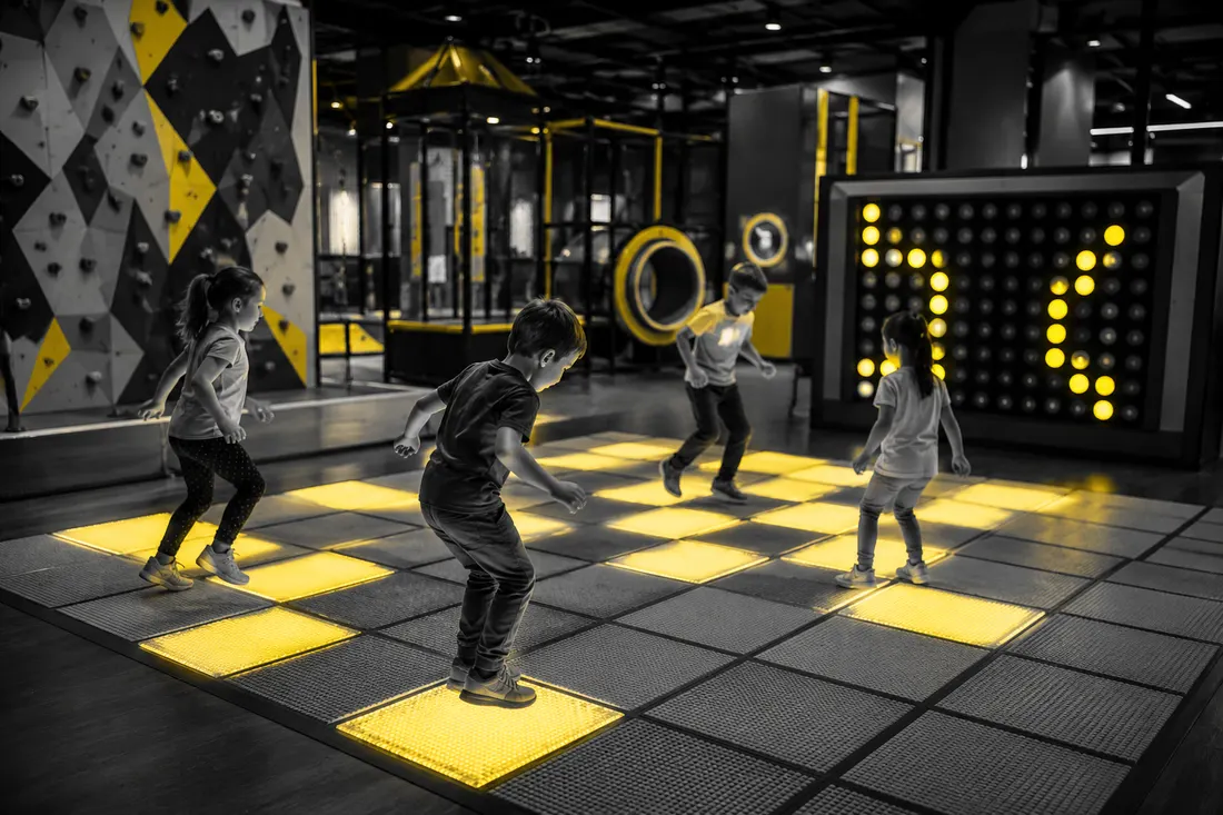 Niños saltando en el piso luminoso de la zona interactiva de AlegríaPlay Hub